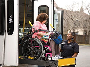 section8-MetroAccess-customer-in-a-wheelchair-boarding-a-MetroAccess-bus-via-a-lift-assisted-by-the-MetroAccess-vehicle-operator