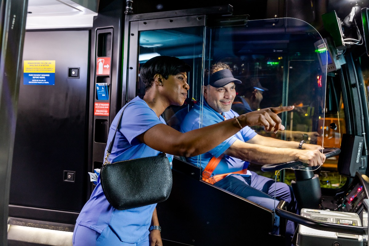 photo of woman getting directions from bus operator at night