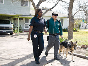 MetroAccess customer with service animal being escorted down a driveway by a MetroAccess vehicle operator